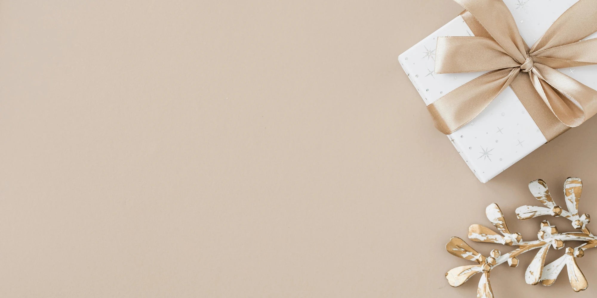 Weiße Geschenkbox mit goldener Schleife und Deko auf beigem Hintergrund – edle, minimalistische Präsentation für stilvolle Geschenkideen und besondere Anlässe