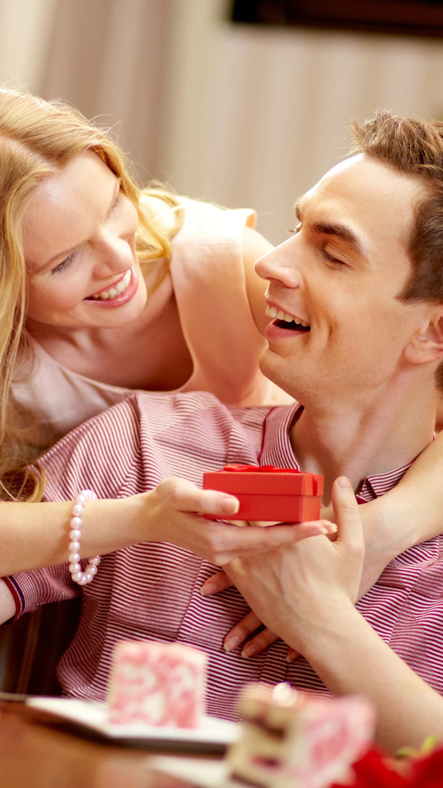 Glückliches Paar, Frau überrascht ihren Partner mit einer roten Amorlune Geschenkbox – perfekte Geschenkidee für besondere Anlässe, Liebe und romantische Momente