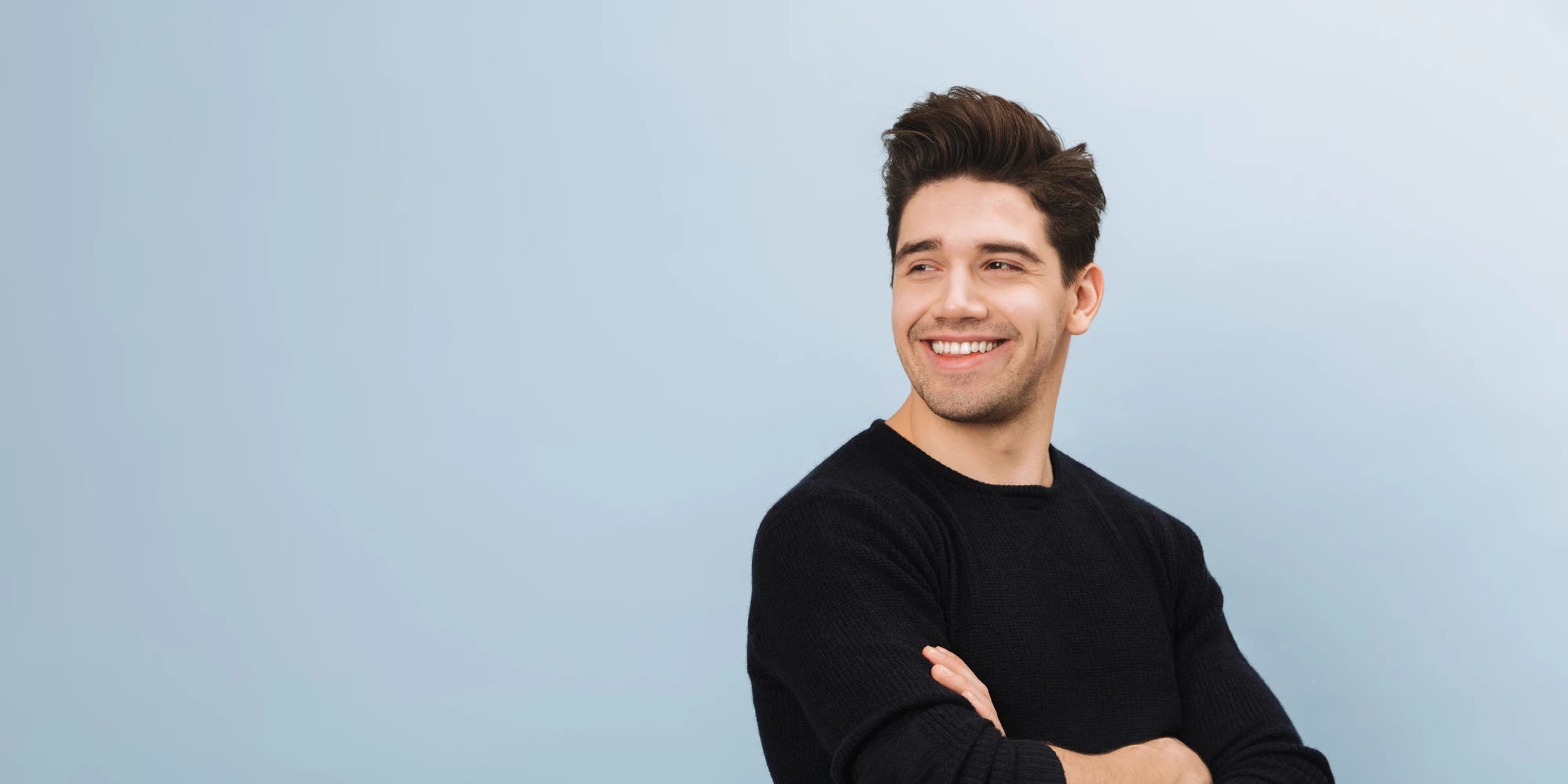 Junger Mann mit dunklem Pullover lächelt und blickt zur Seite – moderne Geschenkidee für Männer, Lebensfreude und Stil von Amorlune