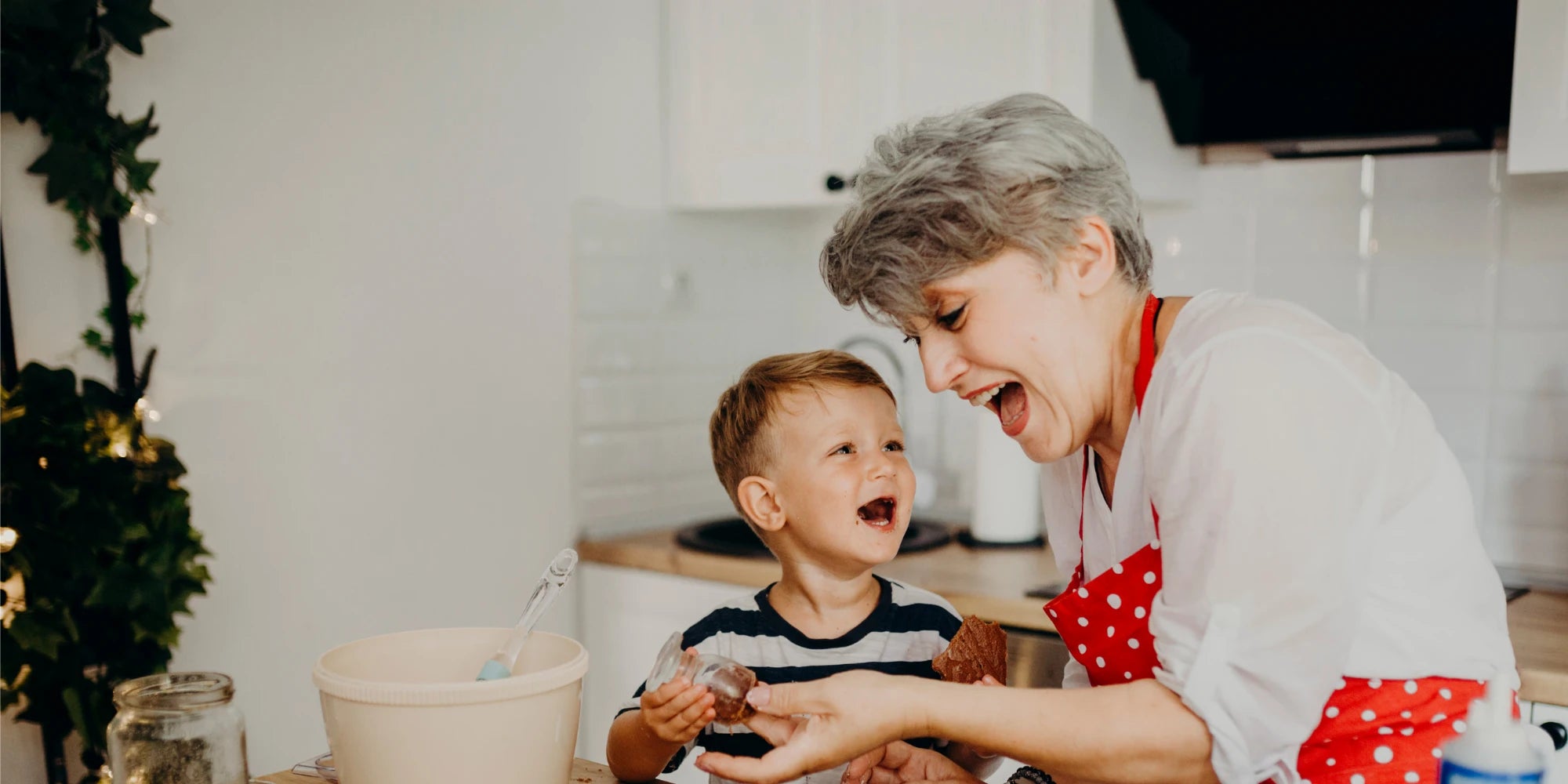 Lachende Großmutter backt mit ihrem Enkel in der Küche – Symbol für Familienzeit, Freude und besondere Geschenkideen für Oma und Enkel von Amorlune