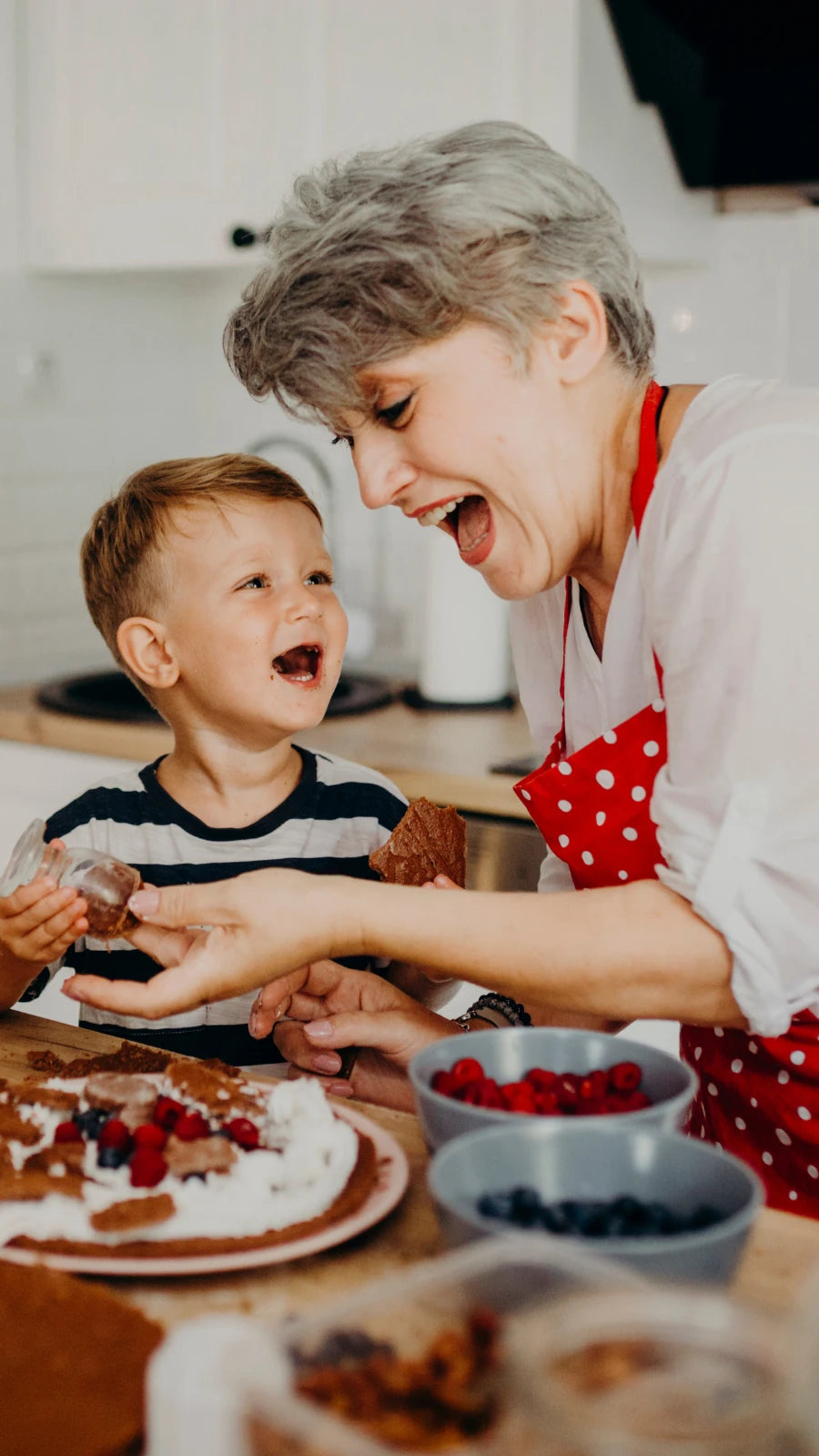 Lachende Großmutter backt mit ihrem Enkel in der Küche – Symbol für Familienzeit, Freude und besondere Geschenkideen für Oma und Enkel von Amorlune