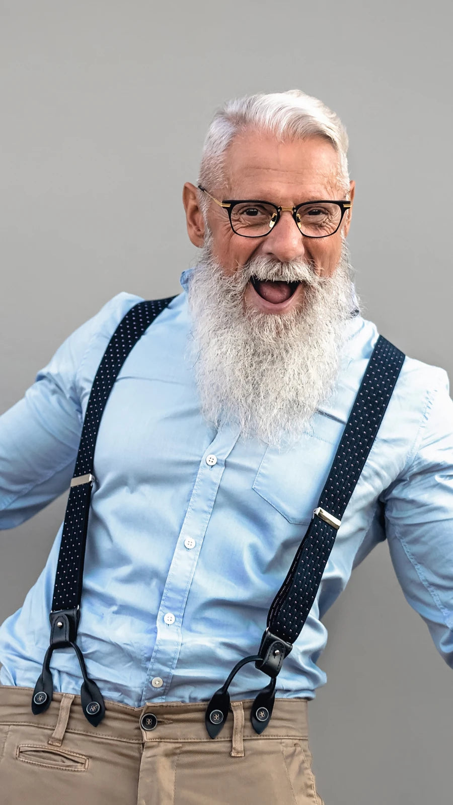 Glücklicher, stilvoller älterer Mann mit weißem Bart, Hosenträgern und Tattoos lacht und freut sich – perfekte Symbolik für Lebensfreude, Stil und besondere Geschenkideen für Opa von Amorlune