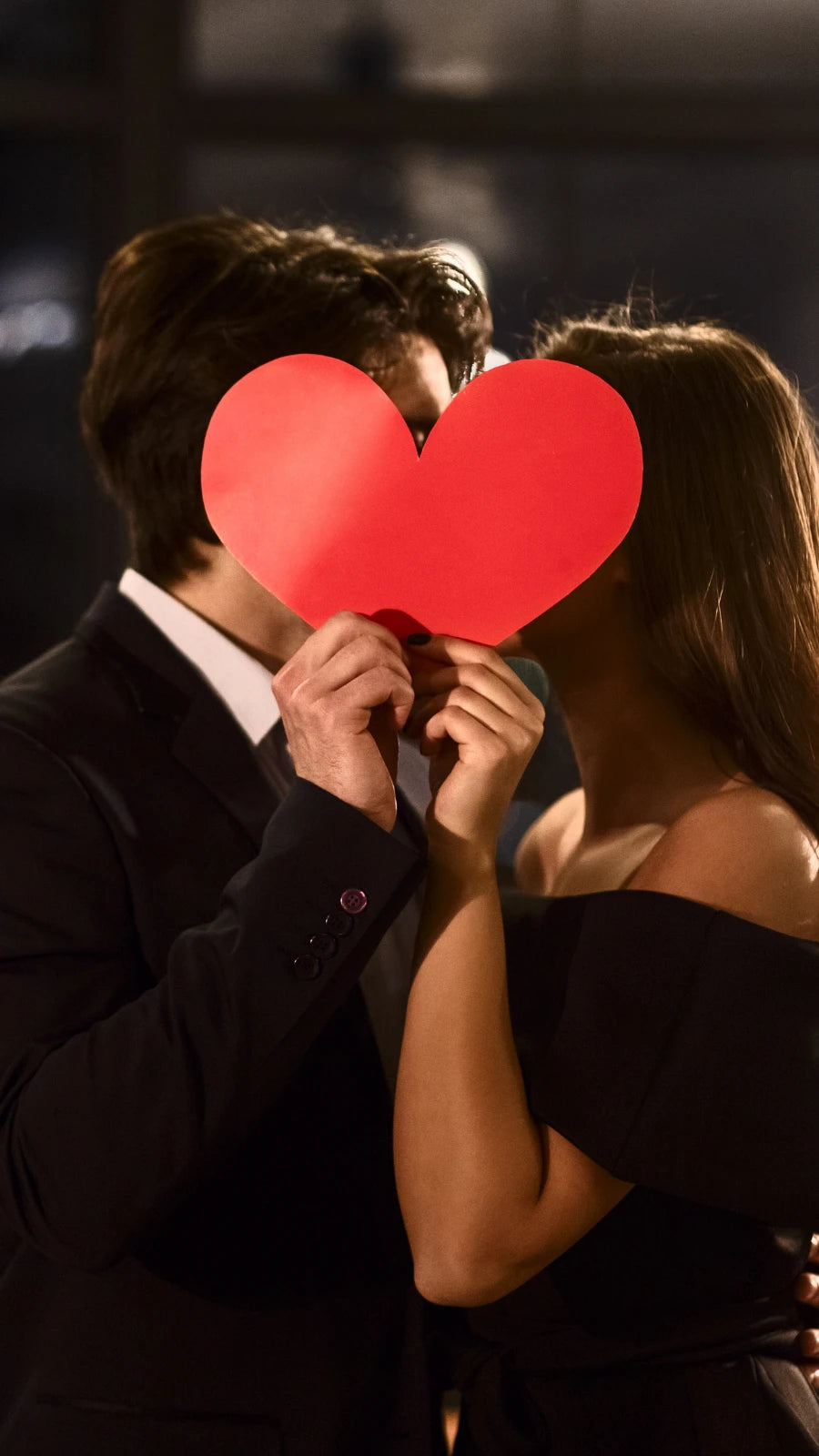 Verliebtes Paar im Abendlicht hält rotes Herz vor dem Gesicht – romantische Stimmung, perfekte Symbolik für Valentinstag, Liebe und besondere Geschenkideen für Paare von Amorlune