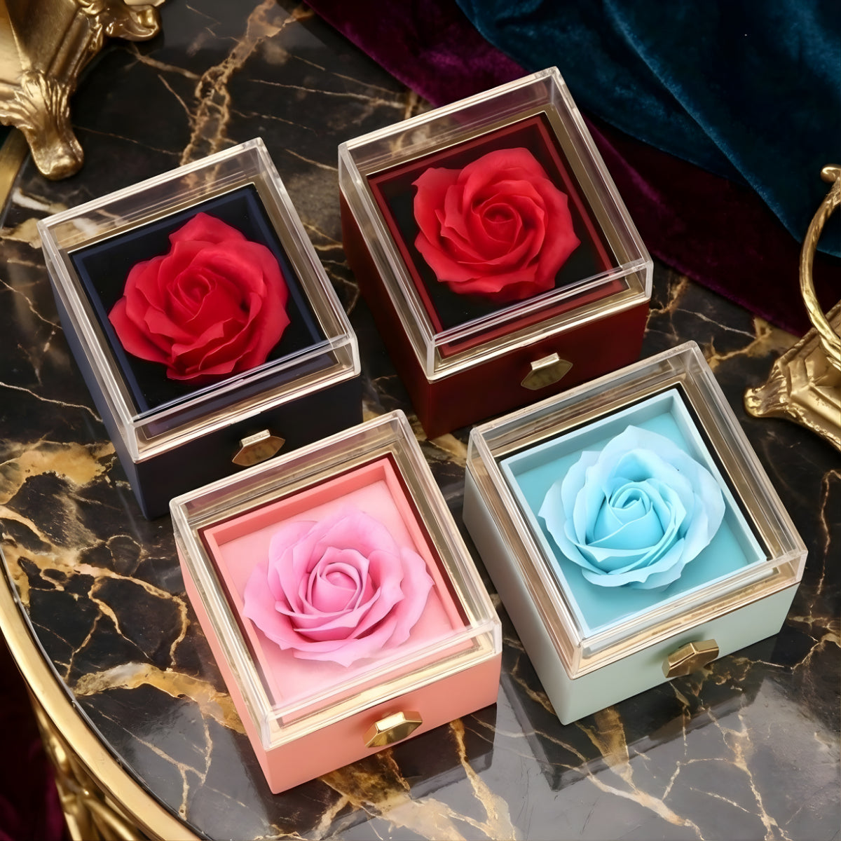 Vier Amorlune Rosenboxen in Rot, Blau, Schwarz und Rosa auf Marmortisch – exklusive Geschenkideen in verschiedenen Farben für besondere Anlässe