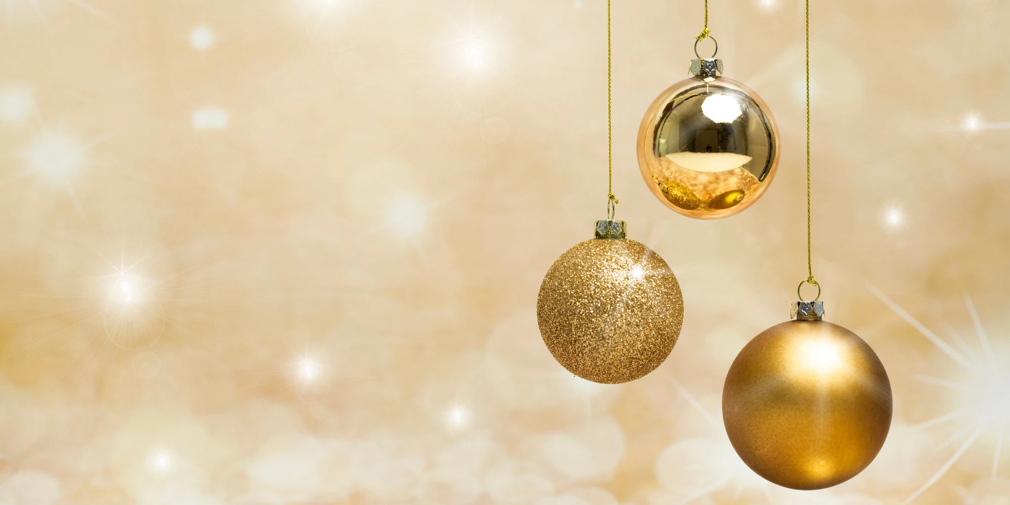 Drei goldene Weihnachtskugeln vor festlichem, goldenem Hintergrund – elegante Weihnachtsdekoration und stimmungsvolle Gestaltungsidee für die Feiertage